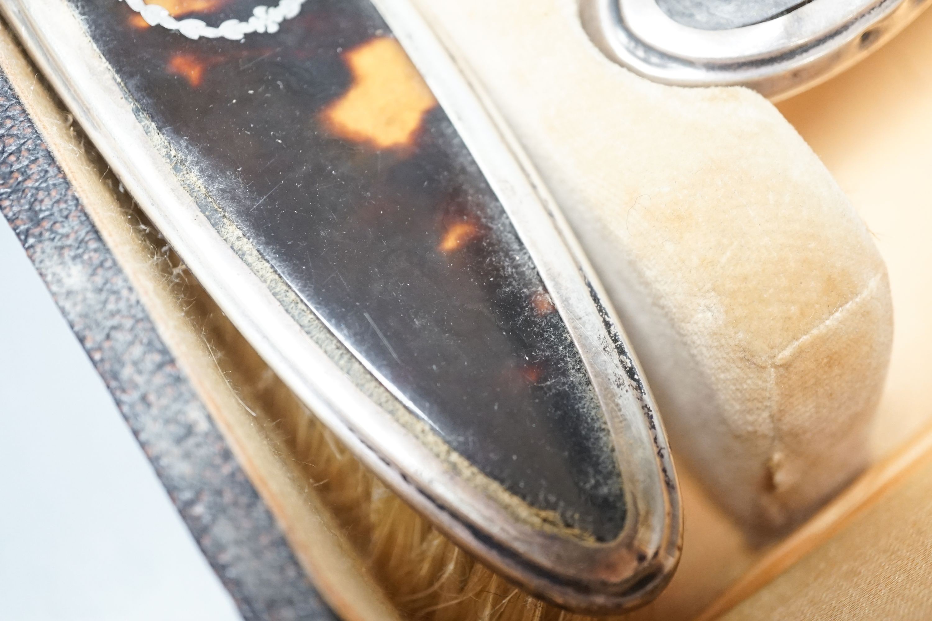 A 1920's cased tortoiseshell and silver mounted mirror and brush set.